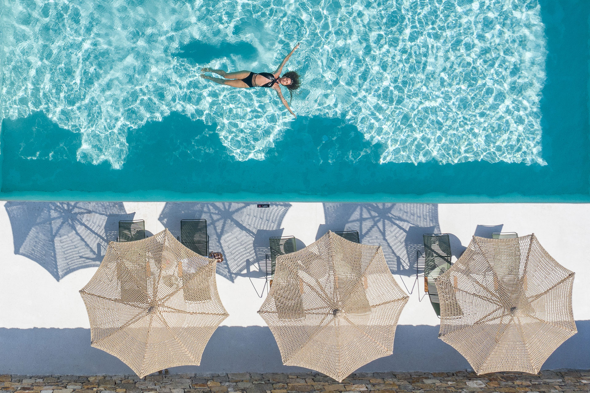 Koukoumi Vegan Hotel sunbeds with umbrellas and visitor enjoying the pool