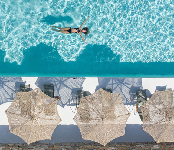 Koukoumi Vegan Hotel sunbeds with umbrellas and visitor enjoying the pool